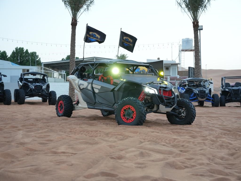 Buggy CanAm Maverick rouge et noir dans le sable du désert de Dubaï , prêt à partir en tour avec ses 4 passagers