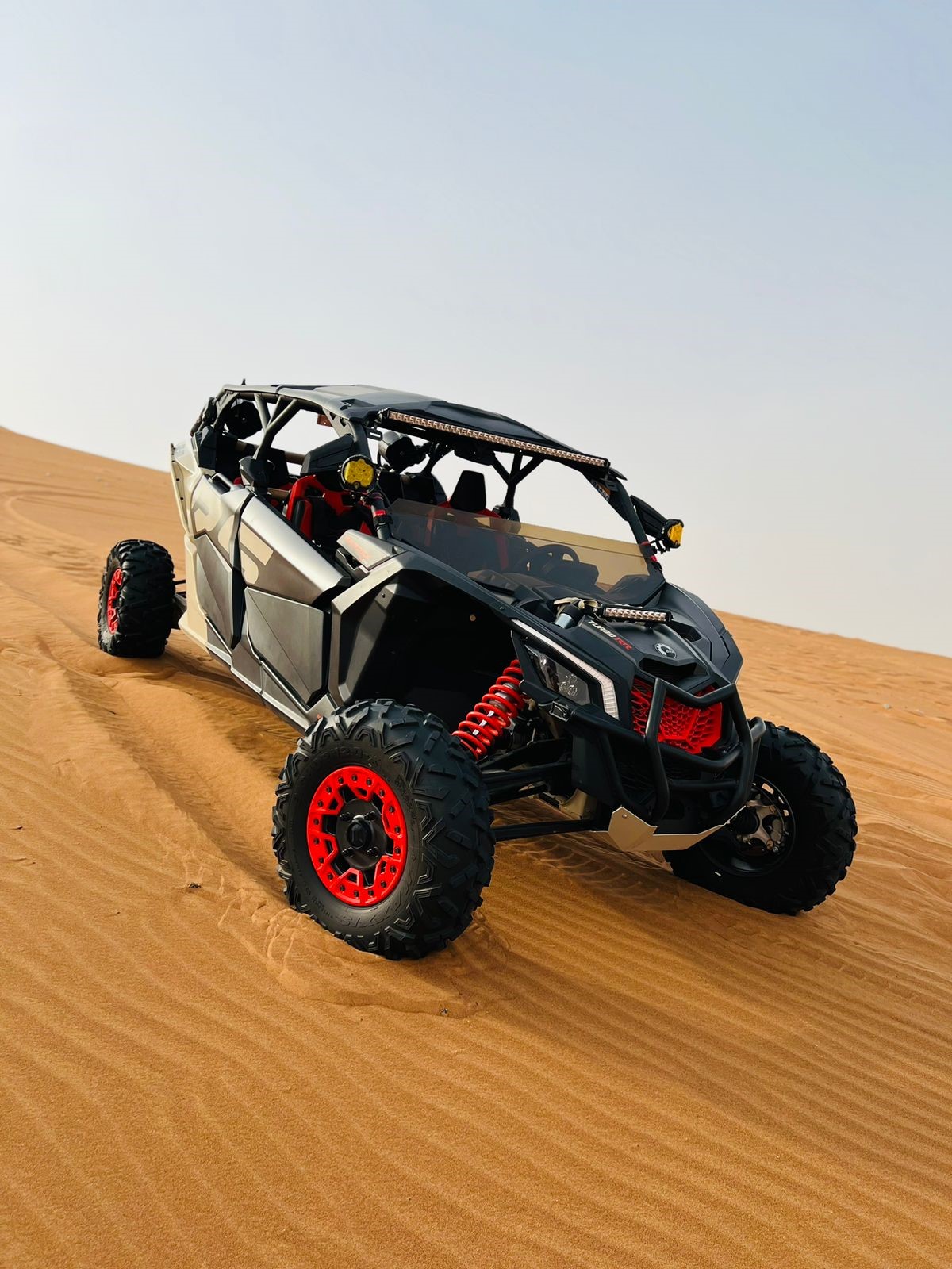 Buggy CanAm Maverick rouge et noir sur une dune du désert de Dubaï , prêt à partir en tour avec ses 4 passagers